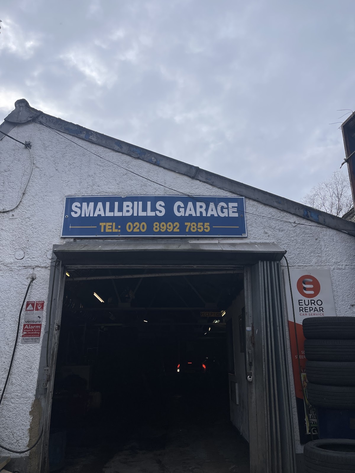 A white Rolls-Royce raised on the ramp inside Smallbills Garage Ltd & Tyre shop on Cannon Works, under the workshop sign